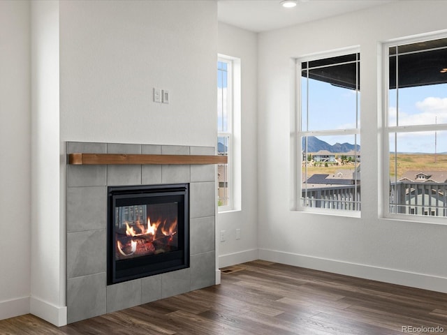 17843 W 93rd Pl, Arvada, CO 80007 - unfurnished living room featuring a tiled fireplace, healthy amount of natural light, and wood finished floors