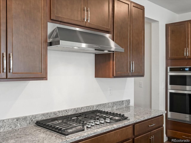 17843 W 93rd Pl, Arvada, CO 80007 - kitchen with range hood, stainless steel appliances, light stone counters, and dark brown cabinetry