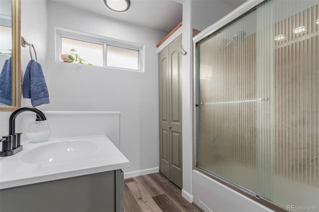 bathroom featuring hardwood / wood-style floors, vanity, and bath / shower combo with glass door