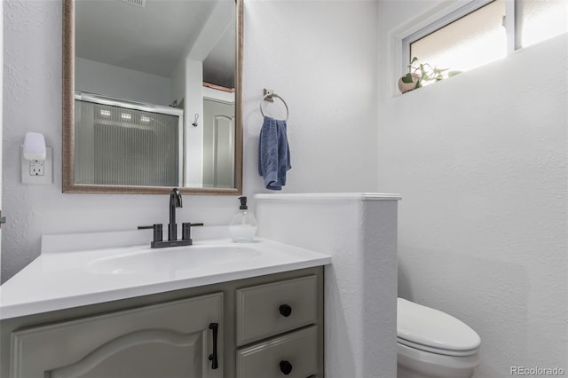 bathroom featuring vanity, toilet, and walk in shower