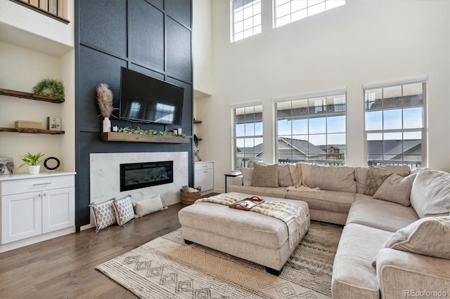 living room featuring hardwood / wood-style flooring, a premium fireplace, and a high ceiling