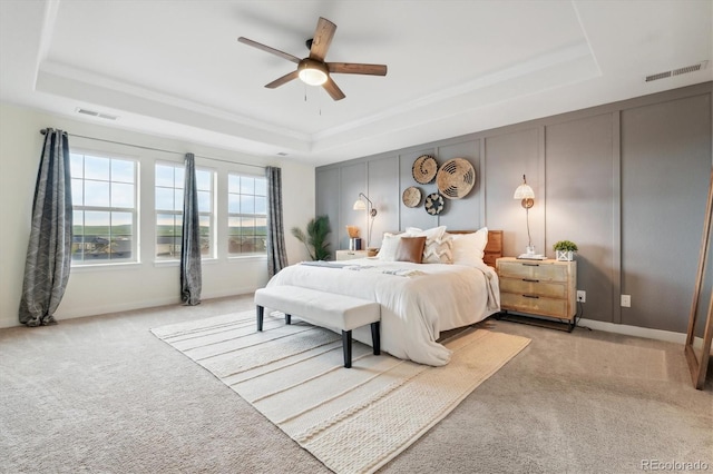 bedroom featuring light carpet, a tray ceiling, and ceiling fan