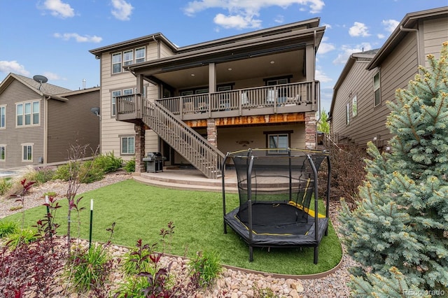 back of house with a trampoline and a lawn