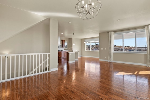 unfurnished living room featuring a notable chandelier and dark hardwood / wood-style flooring