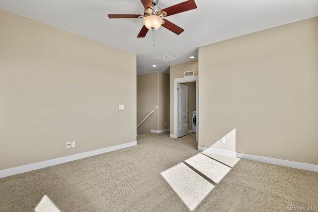 unfurnished room featuring ceiling fan, washer / dryer, and light colored carpet