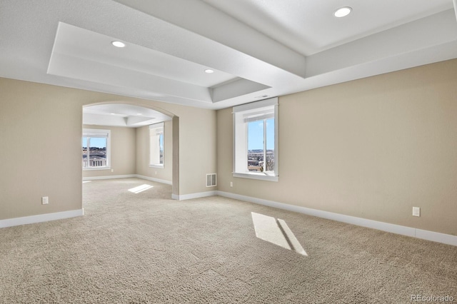 carpeted empty room with a raised ceiling