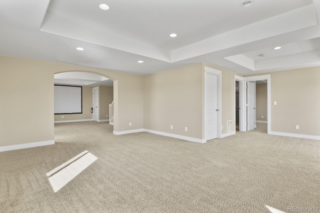 carpeted spare room featuring a tray ceiling