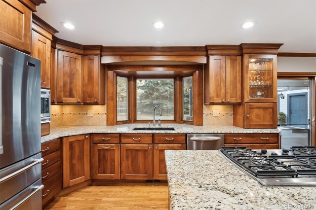 1998 S Harlan Ct, Lakewood, CO 80227 - kitchen with stainless steel appliances, a sink, light wood-style flooring, light stone countertops, and decorative backsplash
