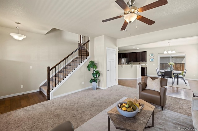 10414 Declaration Dr, Colorado Springs, CO 80925 - carpeted living area featuring stairway, a ceiling fan, a chandelier, and wood finished floors
