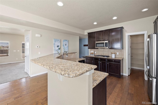 10414 Declaration Dr, Colorado Springs, CO 80925 - kitchen featuring stainless steel appliances, dark wood-style floors, dark brown cabinetry, decorative backsplash, and recessed lighting