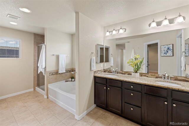 10414 Declaration Dr, Colorado Springs, CO 80925 - full bathroom with a bath, double vanity, a shower stall, a textured ceiling, and tile patterned flooring
