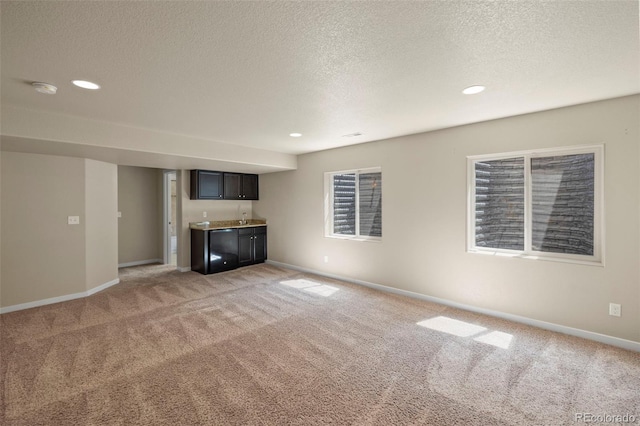10414 Declaration Dr, Colorado Springs, CO 80925 - unfurnished living room featuring light colored carpet, wet bar, a textured ceiling, and recessed lighting