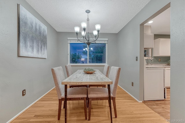 15918 E Flora Pl, Aurora, CO 80013 - dining area featuring washer and clothes dryer, a chandelier, light wood-style flooring, a textured ceiling, and baseboards