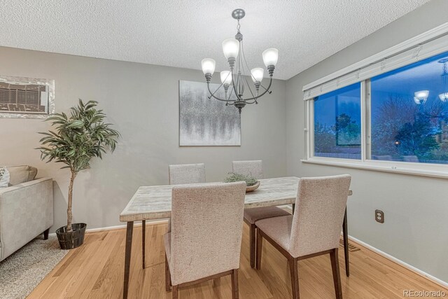 15918 E Flora Pl, Aurora, CO 80013 - dining space featuring a chandelier, light wood-style floors, a textured ceiling, baseboards, and an AC wall unit