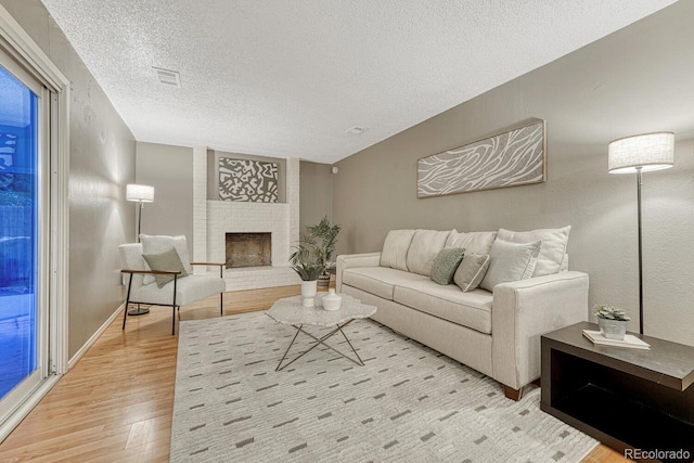 15918 E Flora Pl, Aurora, CO 80013 - living area featuring wood finished floors, a textured ceiling, and a fireplace