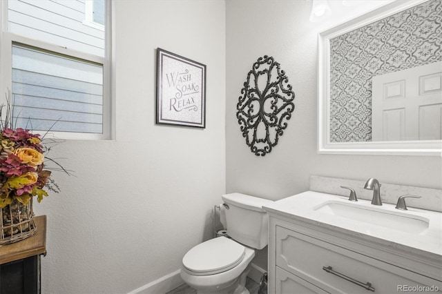bathroom featuring vanity, toilet, and baseboards