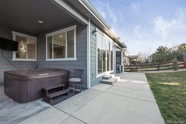 view of side of home featuring a hot tub, a patio, and fence