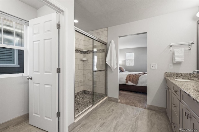 ensuite bathroom with a stall shower, baseboards, and vanity