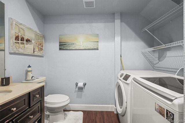 laundry room with washing machine and dryer, dark wood-style flooring, and baseboards