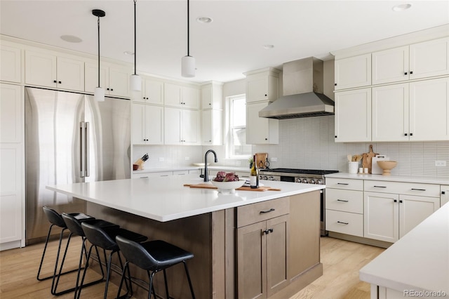 14247 Beebalm Loop, Parker, CO 80134 - kitchen featuring wall chimney exhaust hood, stainless steel appliances, light wood finished floors, backsplash, and light countertops