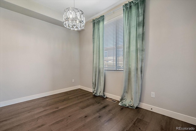 empty room featuring dark hardwood / wood-style flooring and a chandelier