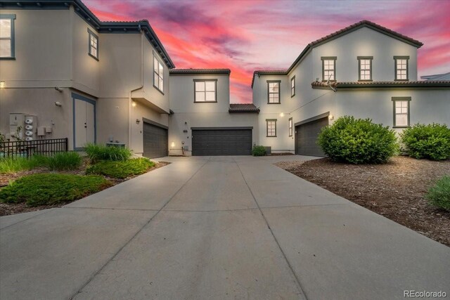 3372 Central Park Blvd, Denver, CO 80238 - view of front of home featuring a garage, driveway, a tile roof, and stucco siding
