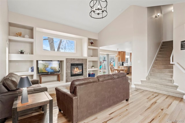 4426 Crow Creek Dr, Colorado Springs, CO 80922 - living area with built in shelves, light wood finished floors, stairs, high vaulted ceiling, and a chandelier