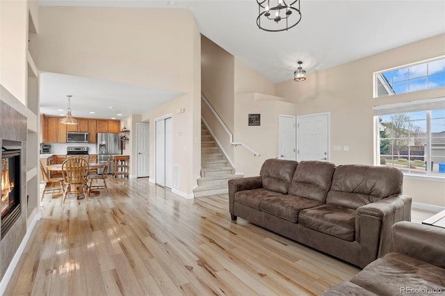 4426 Crow Creek Dr, Colorado Springs, CO 80922 - living area with high vaulted ceiling, light wood-style flooring, a fireplace, stairway, and baseboards