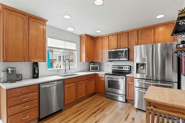 4426 Crow Creek Dr, Colorado Springs, CO 80922 - kitchen featuring appliances with stainless steel finishes, a sink, light countertops, light wood-type flooring, and tasteful backsplash