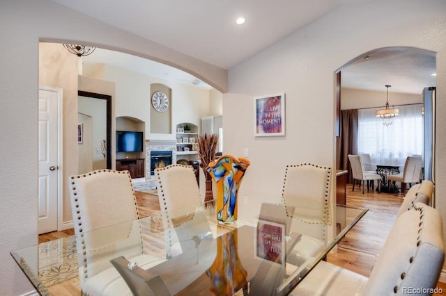 dining room with light hardwood / wood-style floors, vaulted ceiling, and an inviting chandelier