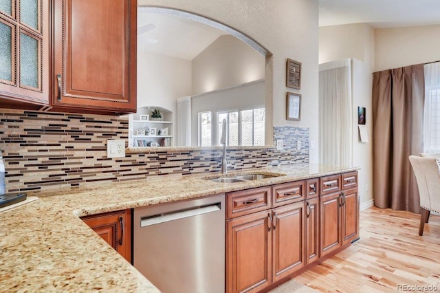 kitchen with light stone countertops, dishwasher, sink, backsplash, and light wood-type flooring