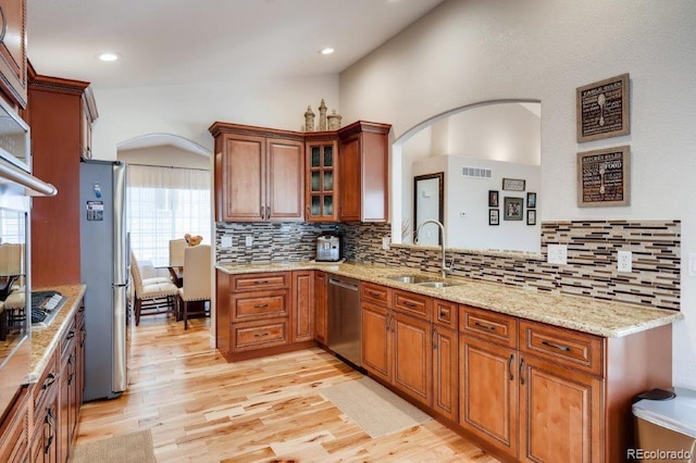 kitchen with sink, vaulted ceiling, decorative backsplash, appliances with stainless steel finishes, and light wood-type flooring