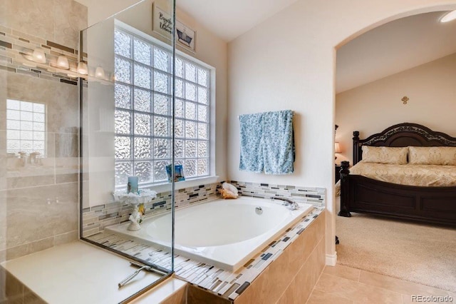 bathroom with tile patterned flooring, tiled tub, and a wealth of natural light