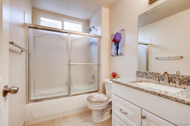 full bathroom featuring tile patterned flooring, vanity, toilet, and bath / shower combo with glass door