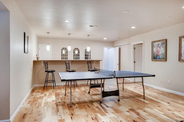 rec room featuring light wood-type flooring and a textured ceiling