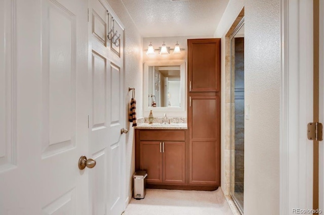 bathroom with a shower with door, vanity, and a textured ceiling