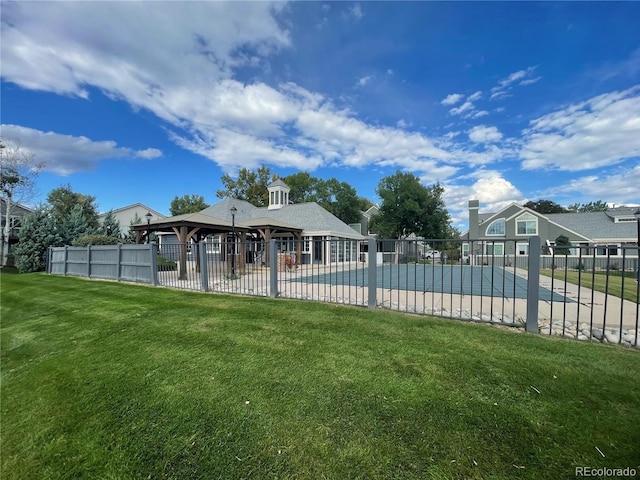 rear view of property with a yard and a covered pool