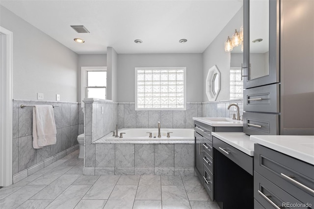 2370 W 152nd Ave, Broomfield, CO 80023 - full bath with marble finish floors, vanity, a bath, a wainscoted wall, and tile walls