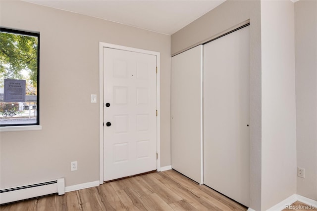 foyer with baseboard heating and light hardwood / wood-style floors