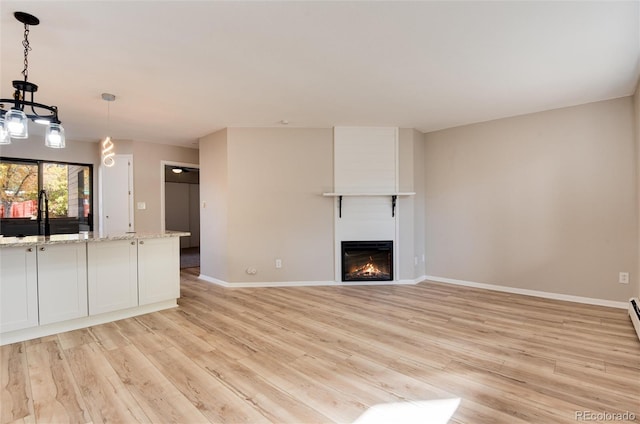 unfurnished living room with light hardwood / wood-style floors, a chandelier, and sink