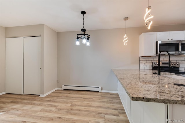 kitchen with light wood-type flooring, appliances with stainless steel finishes, light stone countertops, white cabinets, and baseboard heating