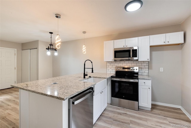 kitchen with kitchen peninsula, appliances with stainless steel finishes, hanging light fixtures, white cabinets, and light wood-type flooring