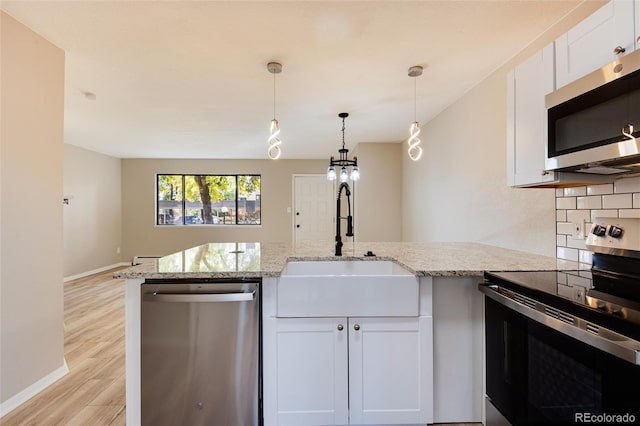 kitchen featuring white cabinetry, appliances with stainless steel finishes, light hardwood / wood-style floors, and light stone counters