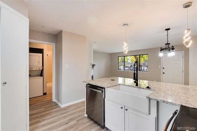 kitchen featuring stainless steel appliances, white cabinetry, light stone countertops, light hardwood / wood-style floors, and stacked washer / drying machine