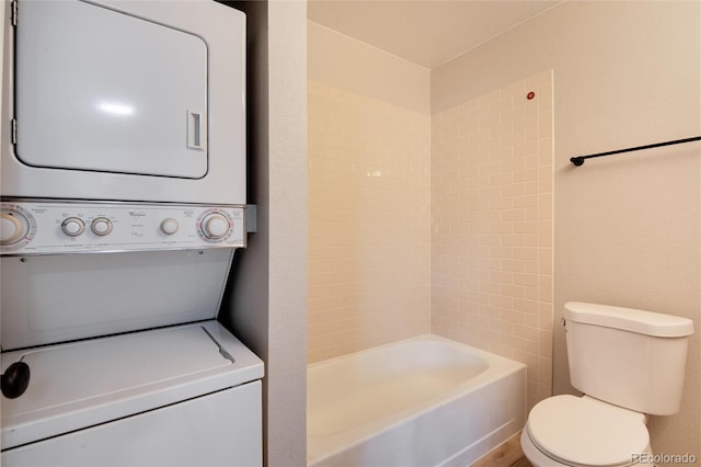 bathroom featuring stacked washer / dryer and toilet