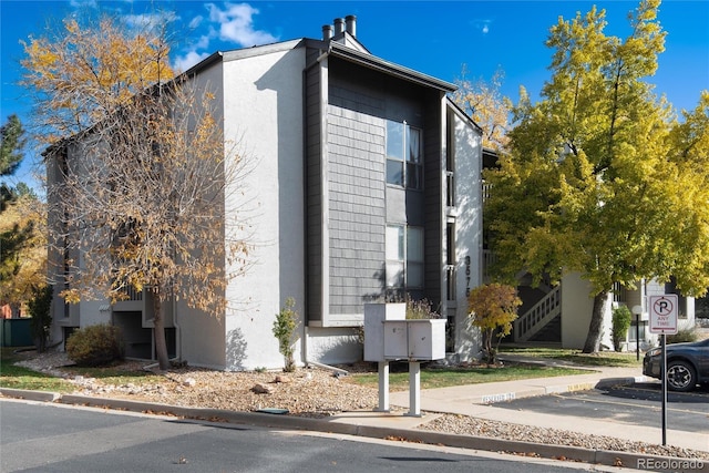 view of home's exterior featuring mail area, uncovered parking, and stucco siding