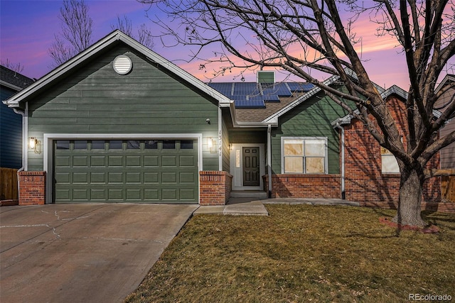 view of front of home with a garage, a yard, and solar panels