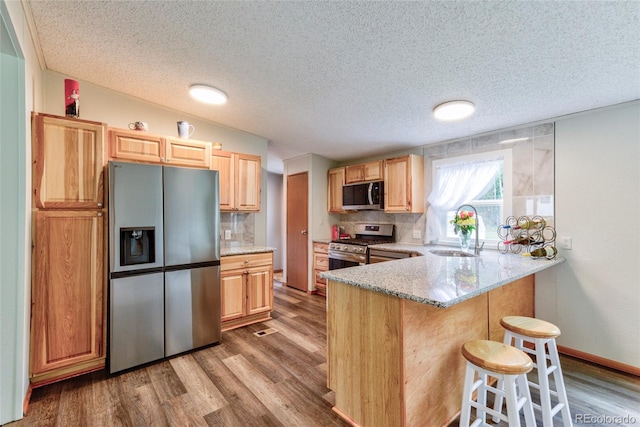 910 W Main St, Buena Vista, CO 81211 - kitchen featuring appliances with stainless steel finishes, wood finished floors, decorative backsplash, and a textured ceiling