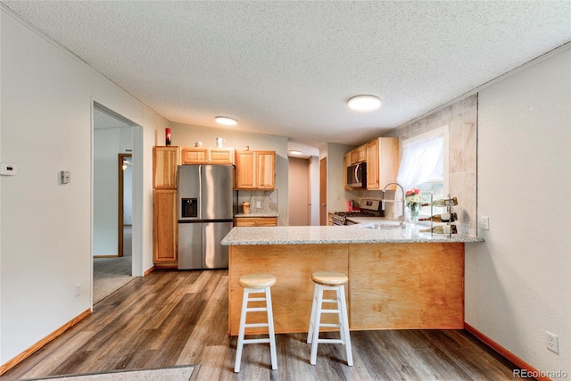 910 W Main St, Buena Vista, CO 81211 - kitchen with appliances with stainless steel finishes, a peninsula, dark wood-type flooring, a textured ceiling, and a breakfast bar