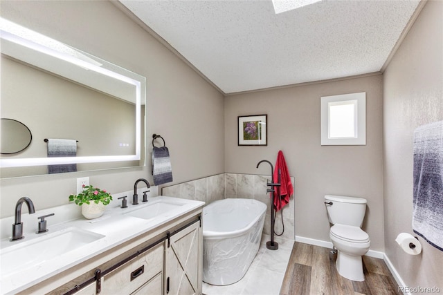 910 W Main St, Buena Vista, CO 81211 - full bathroom featuring a freestanding tub, double vanity, a textured ceiling, lofted ceiling, and wood finished floors